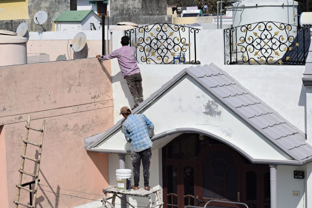 Workers applying white heat reflective roof coating